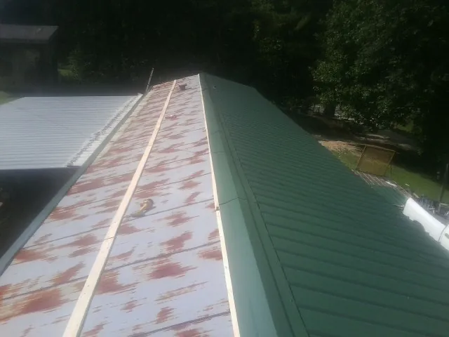 Old rusted panels beside newly installed green metal roofing — Wind Damage Roof Repair by Roofing Brothers in Powhatan