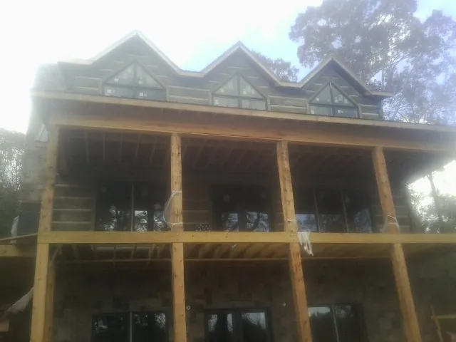 Dormers and porch framing on a large log home under construction — Roof Coating work by our crew in Powhatan