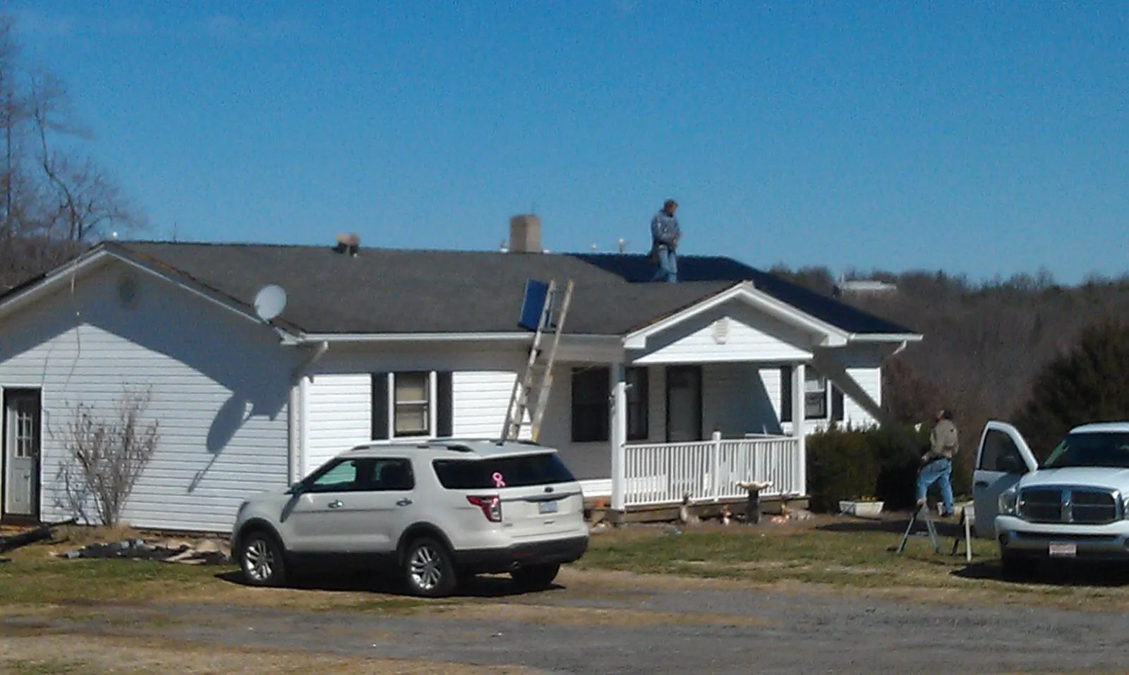 Roofers stripping shingles from a white ranch house roof in Powhatan