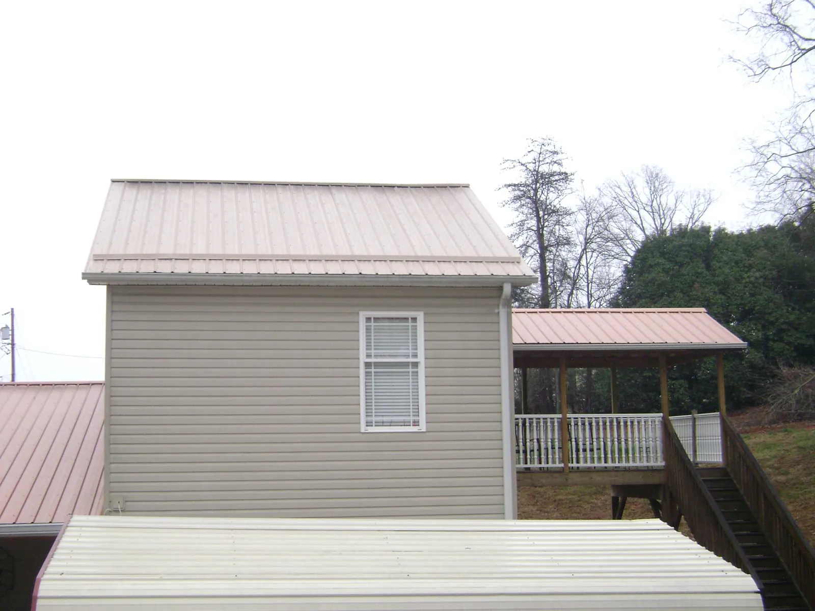 Tan metal roofs on a two story addition and attached porch, from a Roof Replacement job in Powhatan