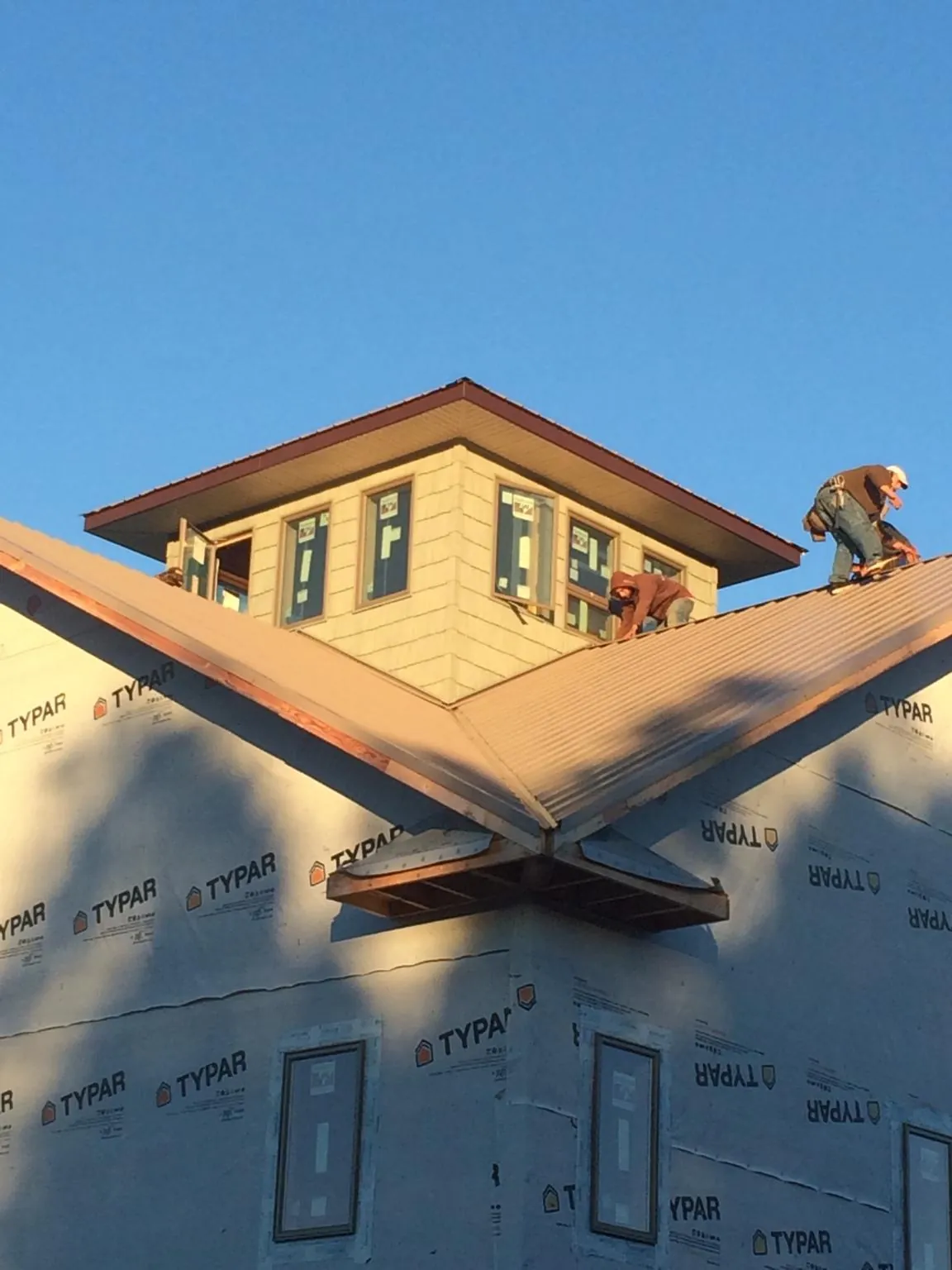 Roofers working around a rooftop cupola on a new metal roof at sunset — Roof Waterproofing in Powhatan by Roofing Brothers